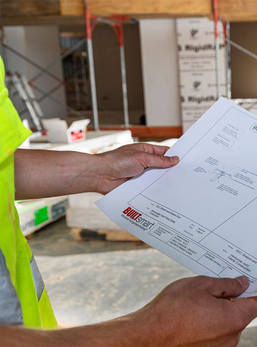 Builder wearing high vis shirt looking at construction plans